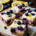 Bright lemon and blueberry cheesecake bars on a white plate