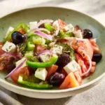 Delicious Greek salad garnished with fresh vegetables and homemade dressing.