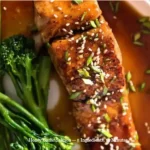 Cooked honey garlic salmon fillet on a plate garnished with herbs