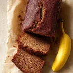 Loaf of JB's banana bread with slices on a wooden table