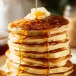 Stack of simple fluffy pancakes topped with syrup and berries